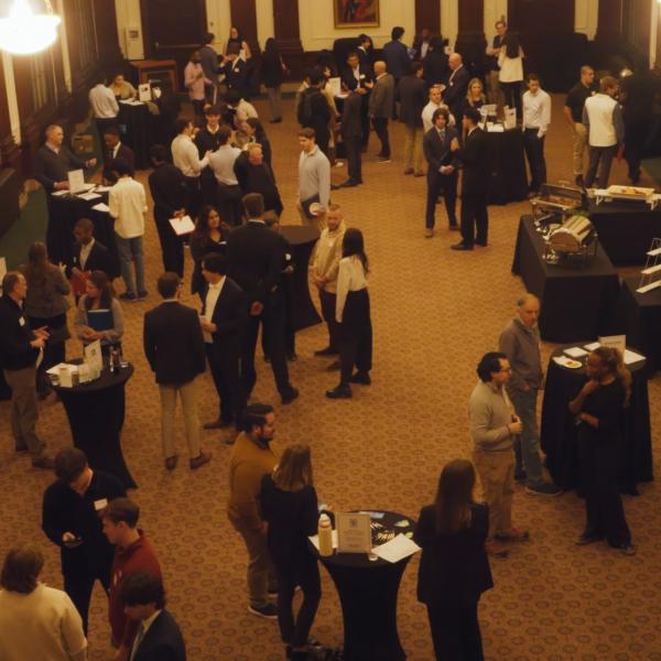 Small crowd of well dressed people standing in a room with tables of food